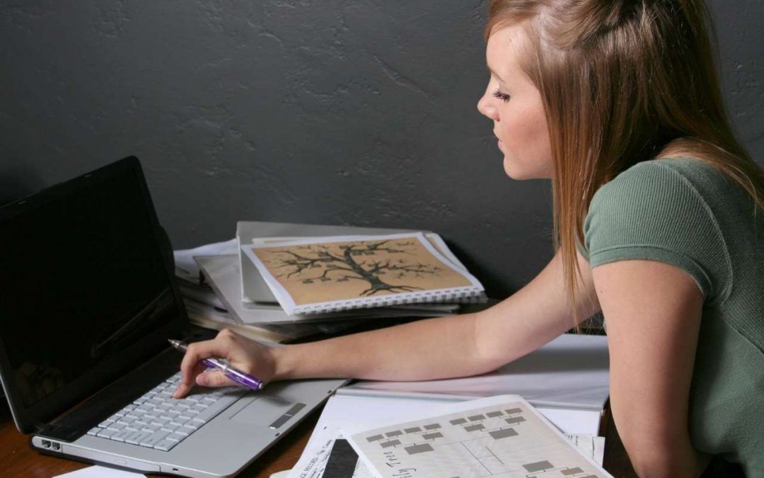 alt=cmujer estudiando el árbol genealógico con fotos y fechas de familiares del curso de psicogenealogia de somapsiconatur
